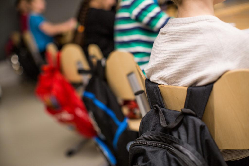 Koulureppuja tuolien selkänojilla.