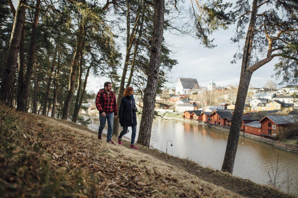 En kvinna och en man promenerar på Näsebacken,i bakgrunden syns kyrkan och de röda strandbodarna.