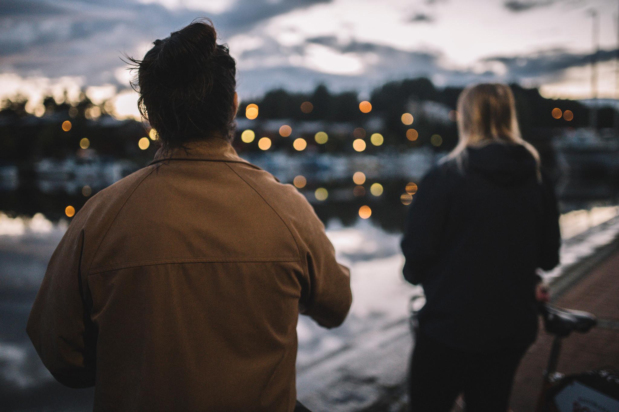 Man och kvinna tittar på stadens ljus på åstranden.