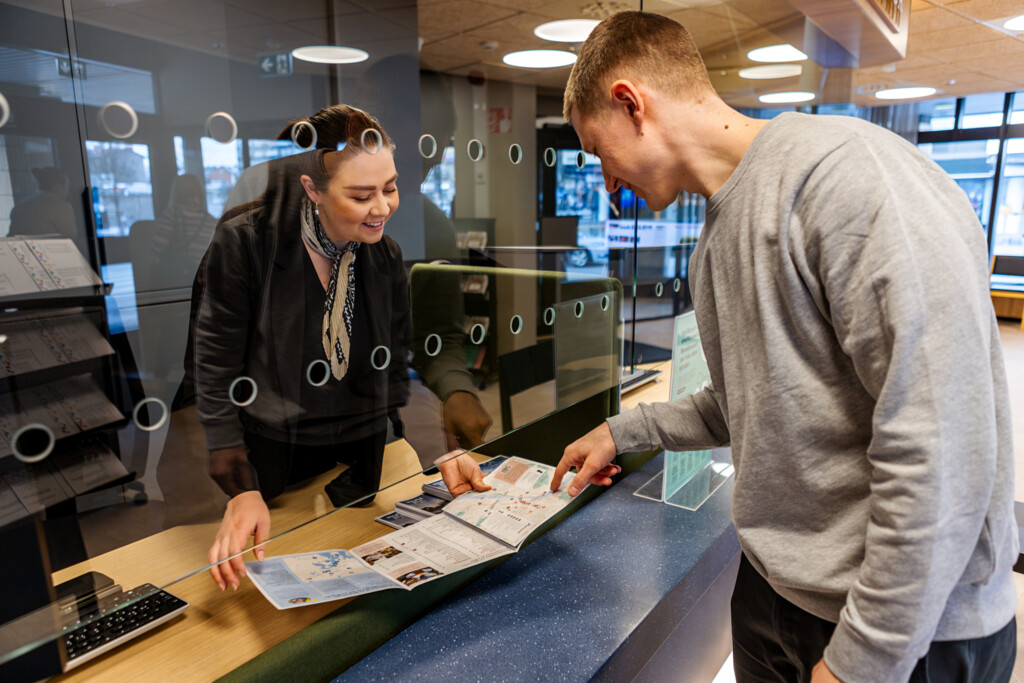 A customer advisor helping a person at the Porvoo Info desk.