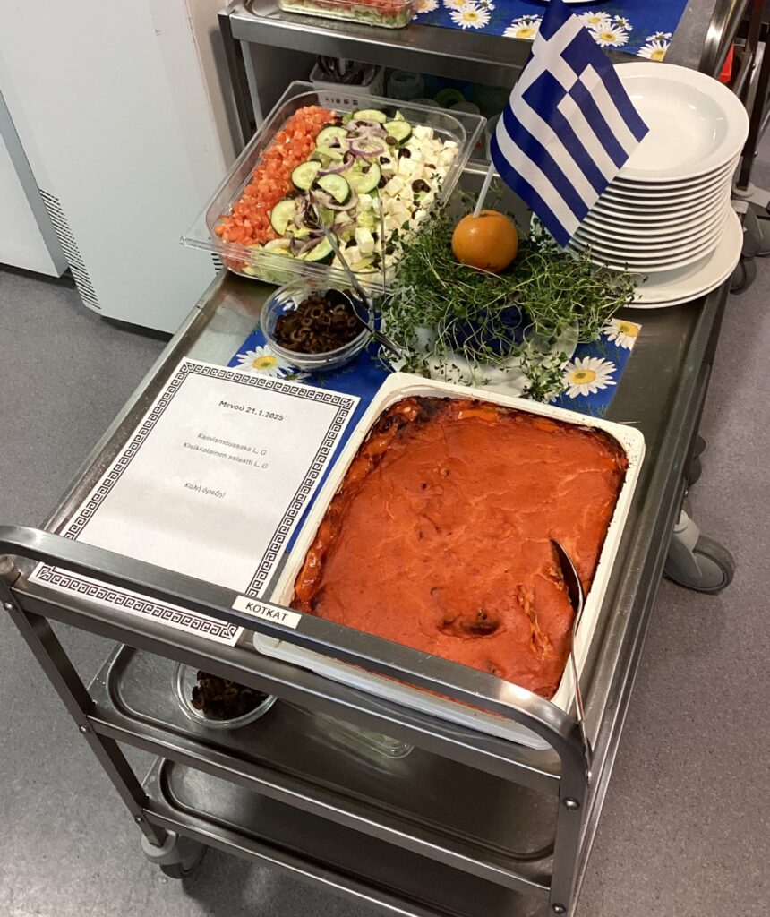 Moussaka, Greek salad, herbs and a Greek flag on a trolley. 